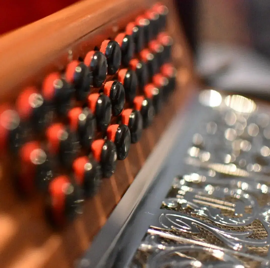 The keyboard of a dark brown melodeon with a silver grille.